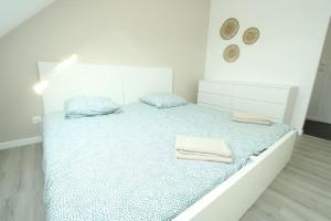 a white bedroom with a bed with two towels on it at Appartement « La brise de Mer » - 50m de la plage in Bray-Dunes