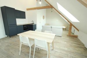 a kitchen with a wooden table and white chairs at Appartement « La brise de Mer » - 50m de la plage in Bray-Dunes