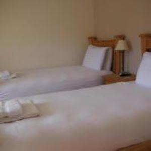 a white bedroom with two beds and a lamp at Inspiration Lodge in Anascaul