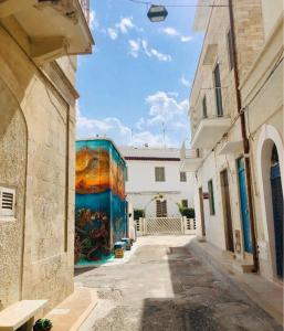 Une allée avec des peintures sur le côté d'un bâtiment dans l'établissement Chicca marina, à Torre Canne