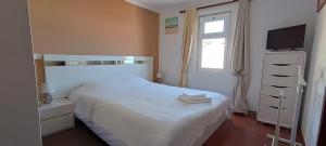 een slaapkamer met een wit bed en een raam bij Reis Magos Beach Caniço Sea line Apartment in Caniço