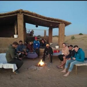 a group of people sitting around a fire at MUSHA PRIVET DESERT HOME STAY in Sām