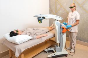 Un hombre de pie junto a un paciente en una cama de hospital. en Poseidon VIP Residence Club Balneo & SPA Resort, en Nesebar