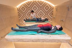 un hombre acostado en una cama en un baño en Poseidon VIP Residence Club Balneo & SPA Resort, en Nesebar