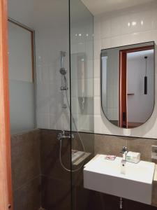 ein Bad mit einer Dusche, einem Waschbecken und einem Spiegel in der Unterkunft The Fields Hotel and Apartment in Seminyak