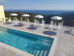 a swimming pool with white chairs and umbrellas at Tenuta Vallina - Golfo di Policastro in Tortorella