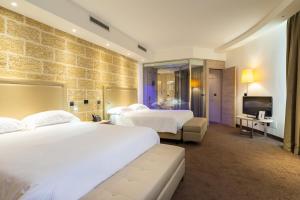 una camera d'albergo con due letti e una televisione di Tenuta Contessa - Relais & Spa a Montalto Uffugo