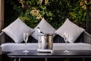 a bottle of wine in a bucket on a table with two glasses at The Londoner Hotel St. Julian's in St. Julianʼs