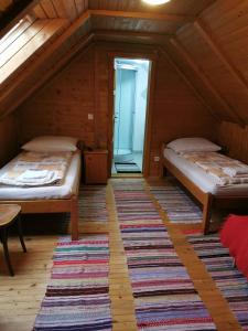 a attic room with two beds and a rug at Emília vendégház in Ciumani