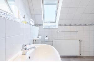 une salle de bain blanche avec un lavabo et une fenêtre dans l'établissement SummerBreak 1 Scharbeutz, à Scharbeutz 4 autres photos