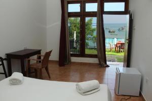 1 dormitorio con cama, mesa y balcón en Perla Fisherman Bay en Weligama