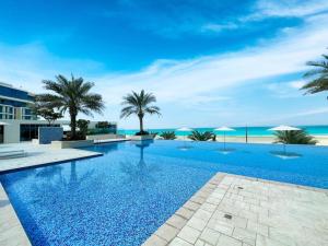 a large swimming pool with palm trees and the ocean at Soul Beach Relaxation! 112MB1 in Abu Dhabi