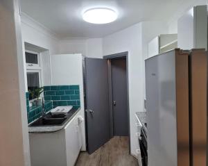 małą kuchnię ze zlewem i zielonymi płytkami w obiekcie Evergreen 2bedroom-sleeps up to 7,2 bathroom w mieście Hornchurch