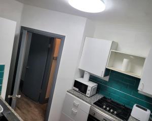 a kitchen with a microwave on a counter next to a door at Evergreen 2bedroom-sleeps up to 7,2 bathroom in Hornchurch