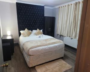 a bedroom with a bed with a black headboard at Evergreen 2bedroom-sleeps up to 7,2 bathroom in Hornchurch