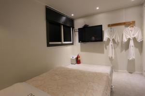 ソウルにあるHotel Sooのベッドルーム1室(ベッド1台、壁に掛けられたシャツ2枚付)
