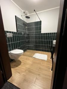 a bathroom with a toilet and a green tiled wall at Cosy Apartments Deluxe in Krakow