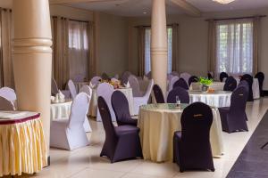 a banquet hall with white tables and purple chairs at Garden Courts Hotel Masaka in Masaka