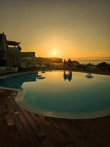 an empty swimming pool with the sunset in the background at Residence New Paradise in Tropea