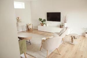 a living room with white furniture and a flat screen tv at Im Fachwerk – Wohlfühlen, Entspannen & Wandern im Grünen in Gladenbach