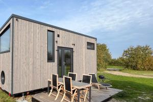 a tiny house with a table and chairs on a deck at Tiny Seaside - Skarrev in Aabenraa