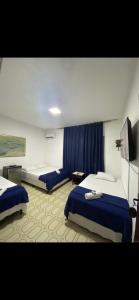 a hotel room with two beds and a tv at Pousada Olívia in São Pedro da Aldeia