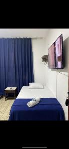 een slaapkamer met een bed en een tv aan de muur bij Pousada Olívia in São Pedro da Aldeia