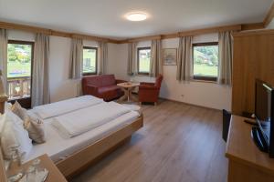 a bedroom with a bed and a chair and a television at Landhotel - Apartments Bauer in Hintergöriach