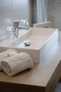 a bathroom sink with a white towel on a wooden counter at Landhotel - Apartments Bauer in Hintergöriach