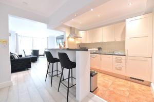 a kitchen with bar stools and a living room at Colindale Retreat, Sleeps 6 people in Colindale