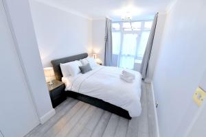 a bedroom with a bed with white sheets and a window at Colindale Retreat, Sleeps 6 people in Colindale