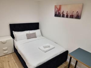 a bedroom with a white bed with a black headboard at Open plan studio with garden in Milton