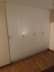 Habitación con armarios blancos y suelo de madera. en Trevlig lägenhet i Kista en Estocolmo