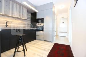 a kitchen with black and white cabinets and a stool at Einpark Fabulous Apartment with Private parking in Bratislava