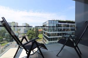 two chairs on a balcony with a view of a building at Einpark Fabulous Apartment with Private parking in Bratislava