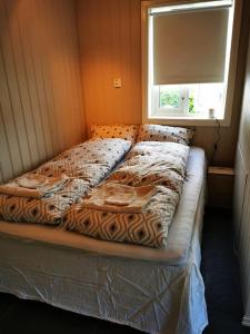 a large bed in a room with a window at Nydelig lite hus med egen vedfyrt baksteovn. in Kaupanger