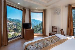 una camera con letto, TV e ampie finestre di Rock Castle By DLS Hotels a Shimla