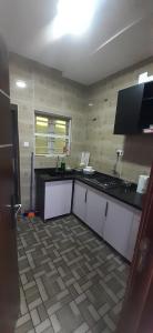 a kitchen with white cabinets and a black counter top at HEN - CAP SERVICED APARTMETS in Agege