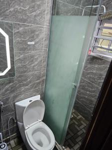 uma casa de banho com um WC e uma porta de vidro em HEN - CAP SERVICED APARTMETS em Agege