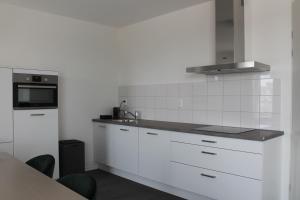 eine weiße Küche mit einer Spüle und einer Mikrowelle in der Unterkunft Trompstraat Eindhoven in Eindhoven