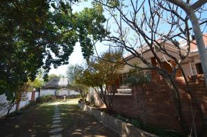 a house with a brick wall and a yard at ParadiseGarden Backpackers in Windhoek