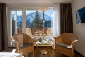 アローザにあるSunstar Hotel Arosaの椅子2脚、テーブル、窓が備わる客室です。