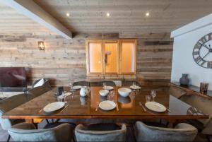 comedor con mesa, sillas y reloj en Chalet 24 pers sur la route du tour, en LʼHuez