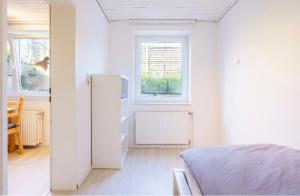 ein weißes Schlafzimmer mit einem Bett und einem Fenster in der Unterkunft SummerBreak 3 Scharbeutz in Scharbeutz