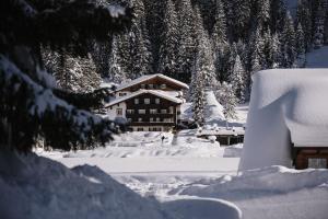 uma casa coberta de neve com árvores ao fundo em Alpenhotel Heimspitze em Gargellen