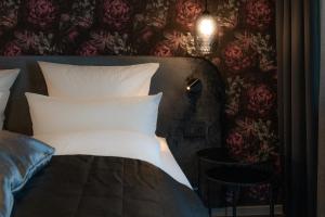 Bett mit weißen Kissen in einem Zimmer mit Blumentapete in der Unterkunft Parkhotel in Bad Waldsee