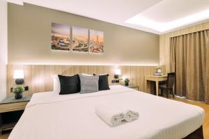 a bedroom with a large white bed and a desk at Tori crown hotel in Bangkok