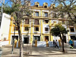 un edificio giallo con persone che camminano davanti di Hispalis Alfonso X a Siviglia