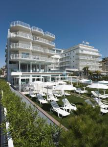 eine Gruppe von Liegestühlen und Sonnenschirmen vor einem Gebäude in der Unterkunft Hotel Le Soleil in Lido di Jesolo