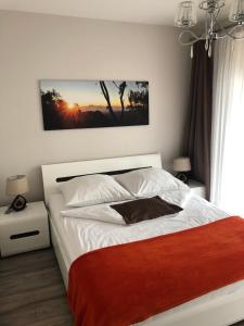 a bedroom with a white bed with a red blanket at Apartamenty MAJA Nowy Targ in Nowy Targ